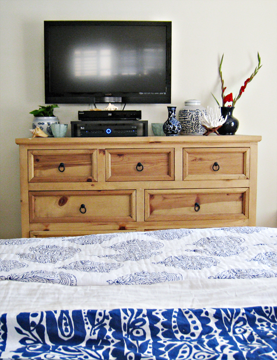 large rustic dresser+blue and white floral bedding+mounted flatscreen tv+porcelain vases