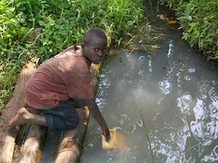 A young boy collects dirty water from an open source