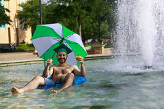 0420 Guy floats in fountain with umbrella, OJ, and graduation cap