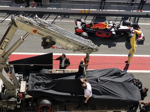 Red Bull passes the rescued McLaren as it returns to the garage at Formula One Winter Testing